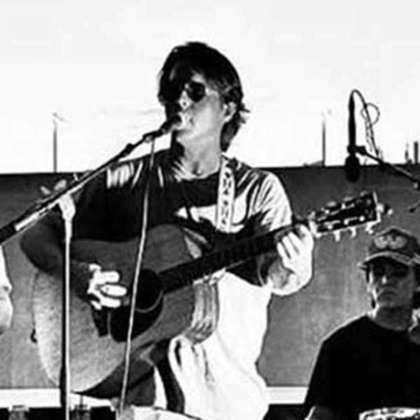 Black and white photo of Will Slater singing lead while playing guitar.