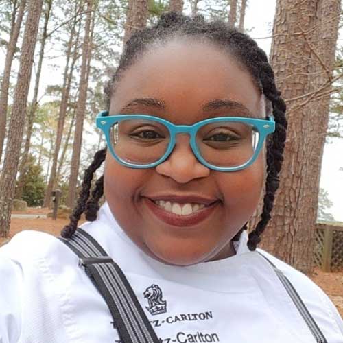 Restaurant Chef Justine Alexander stands smiling with Lake Oconee in the background.