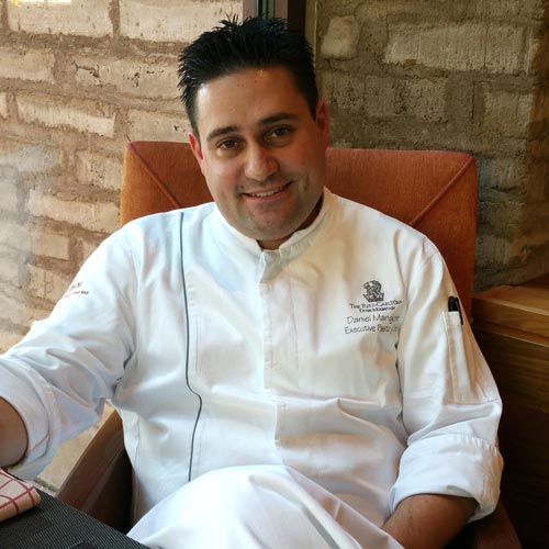 JW Marriott Executive Pasty Chef Daniel Mangione sitting outside a luxury hotel's dinning area.