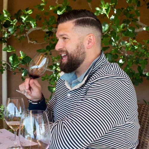 Portrait of Table at the Lake co-owner Jon Altizer-Bieger smiling and holding a glass of wine
