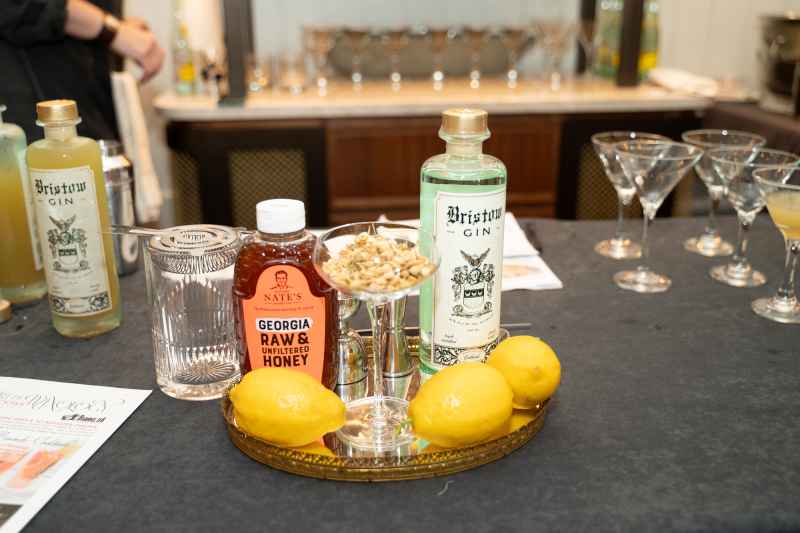 A bottle of Bristow gin and Georgia wild honey sit on a serving tray accompanied by lemons and a martini glass with nuts.