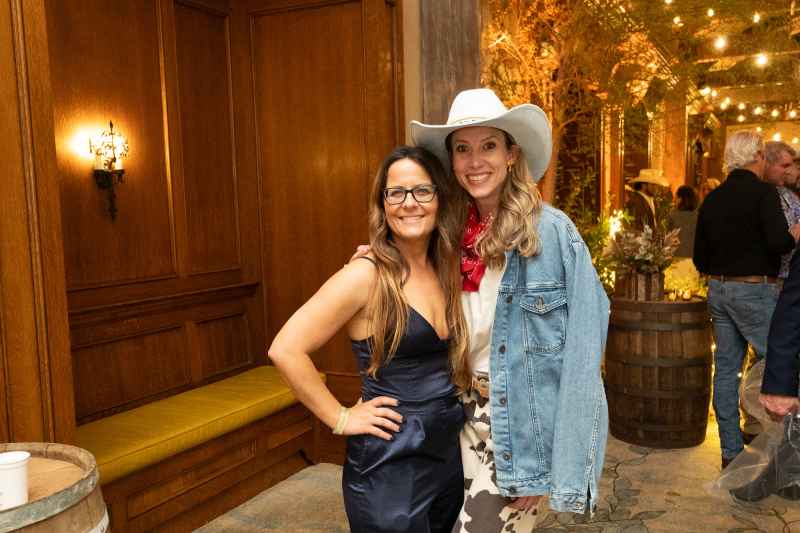 Two women decked out in western wear pose for he camera before heading in to the launch party.