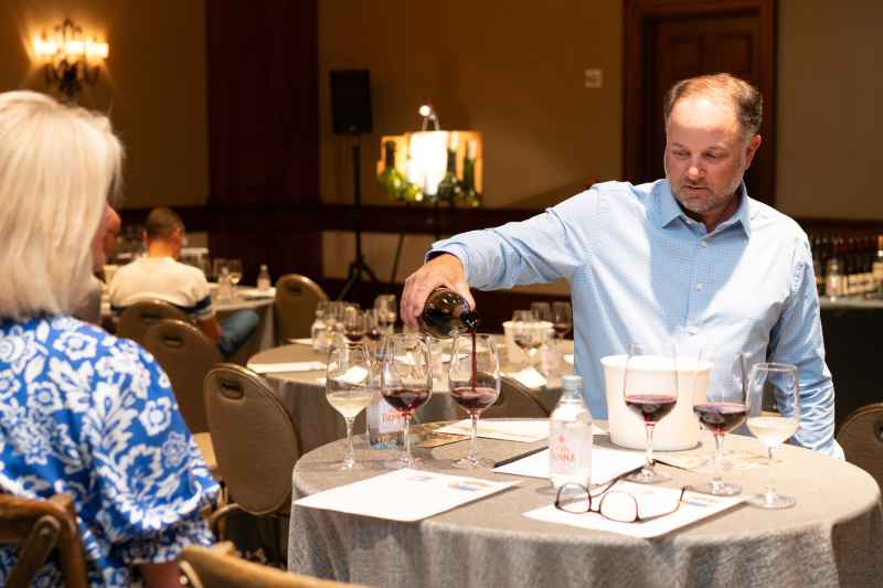 Matt Garafalo, owner of The Oconee Cellar, pours a deep red wine for an attendee of The Private Wine Tasting.